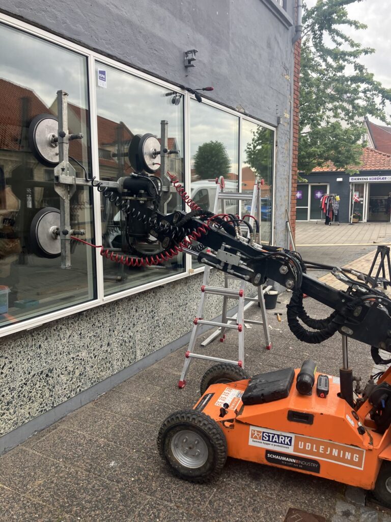Glasrobot monterer store ruder i en butiksfacade