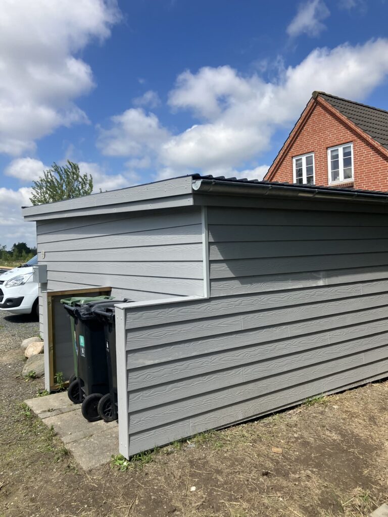 Grå carport med skur set fra siden med affaldsskjul