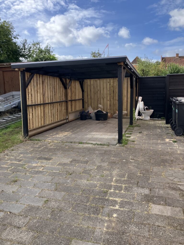 Carport i træ med sort stolpe og bjælke