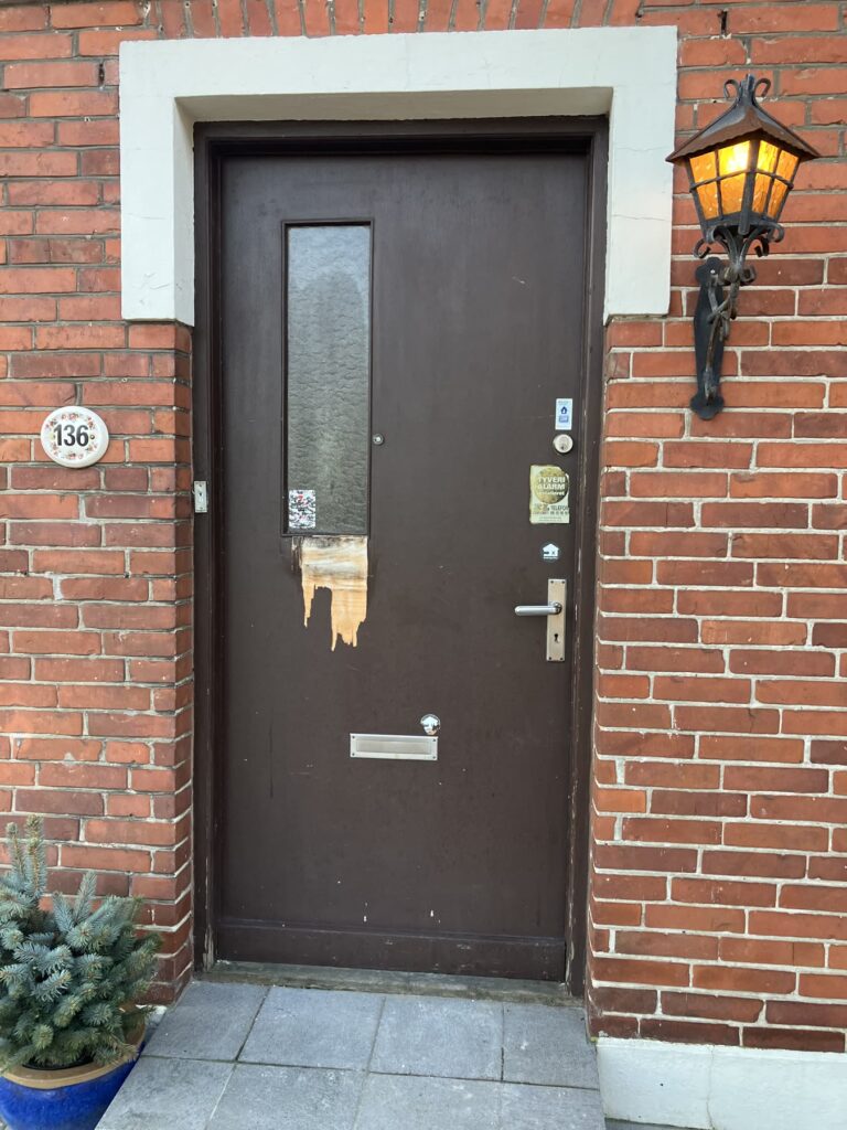 Gammel brun hoveddør i en rød murstensfacade