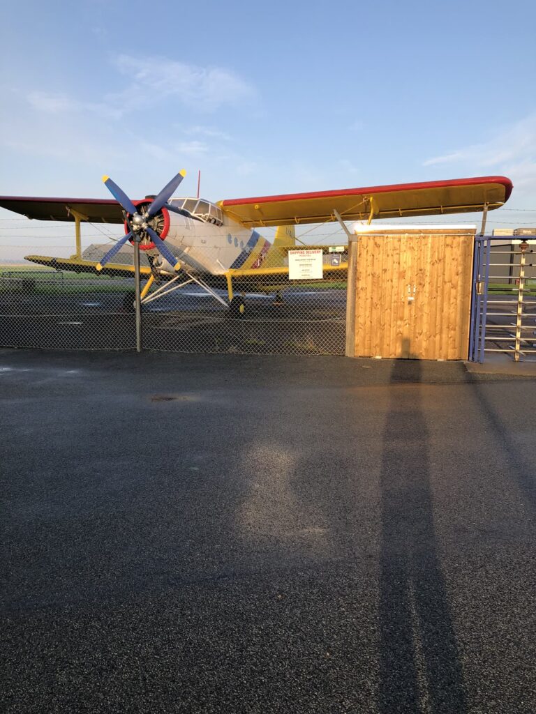 Træskur på en flyveplads med et gammelt dobbeltdækkerfly foran
