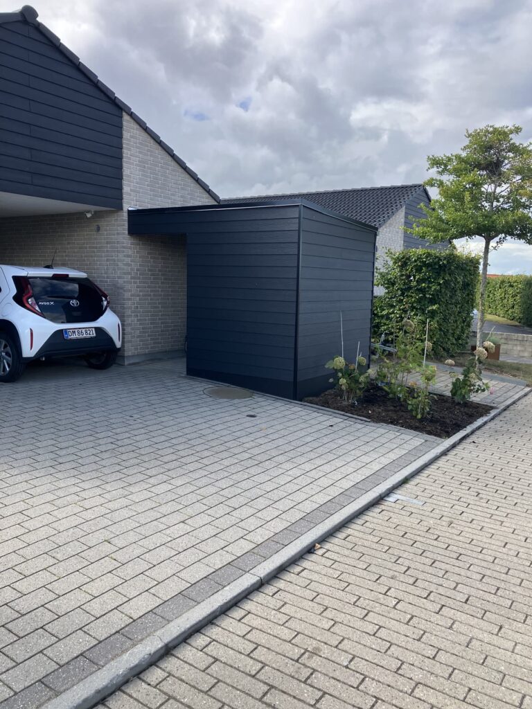 Sort skur ved en carport til et rækkehus