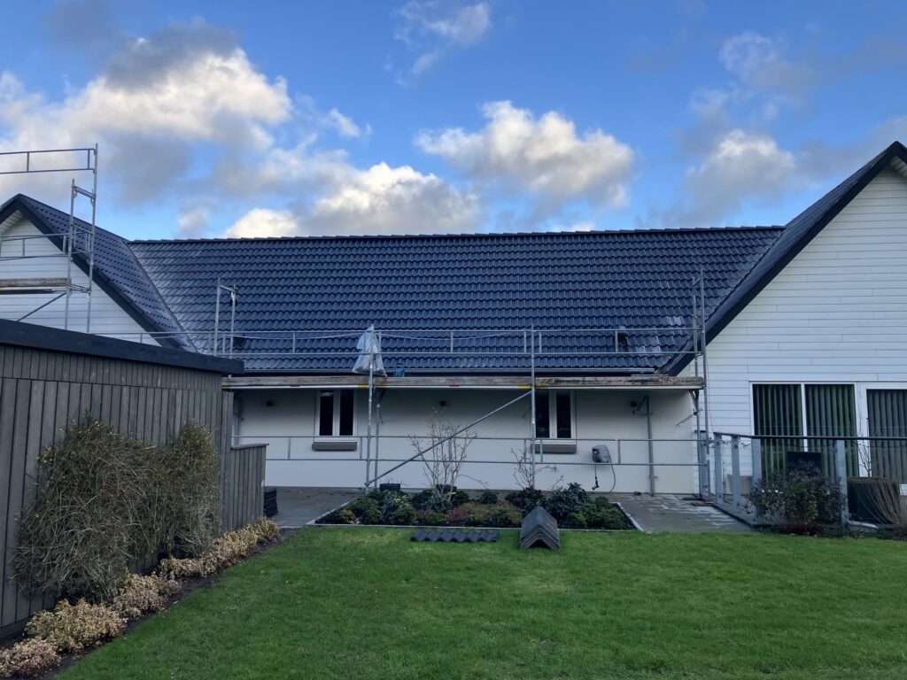 Langt hus med nyt sort tag set fra haven