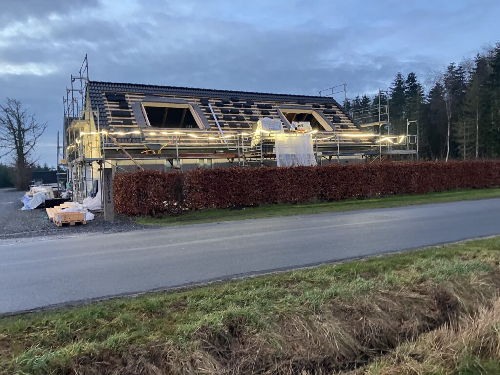 Langt hus med stillads og tag under udskiftning