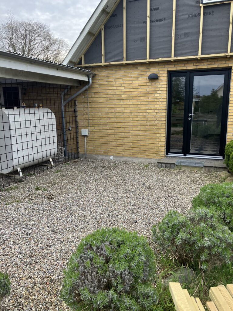 Grusbelagt areal ved en gul villa før terrassen
